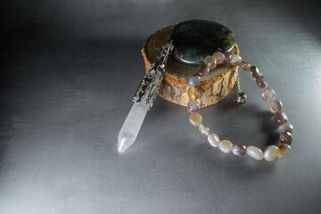 A powerful arrangement of a labradorite stone, crystal quartz pendulum, and agate bracelet, symbolizing balance, healing energy, and spiritual connection. Perfect for mystical and wellness themes.