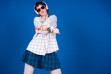 Young woman dancing and singing with pliers as microphone on blue background