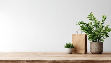 A minimalist scene features a wooden table against a white wall, showcasing a small potted plant, a paper bag, and a larger potted plant