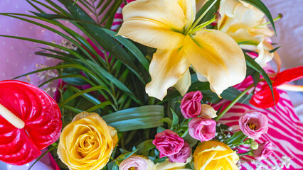 A colourful bouquet featuring a mix of vibrant spring flowers, including yellow , pink roses and orchids.
