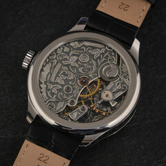High-quality macro photo of a stylish wristwatch turned back side up, featuring an open mechanical...