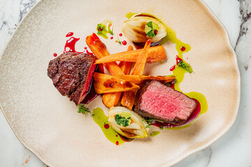 A gourmet dish of tender beef, roasted carrots, and colorful sauces highlights culinary skill
