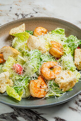 Crisp romaine lettuce, tender shrimp, and savory cheese create a delightful salad on a marble table