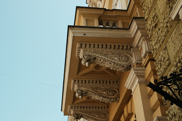 Close-up of ornate architectural details on a historical building in Subotica, Serbia. Classical corbels and intricate stucco work supporting a balcony, showcasing the elegance of neoclassical design. © Ekaterina