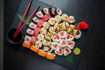 A vibrant array of sushi rolls with diverse colors and flavors on a dark surface