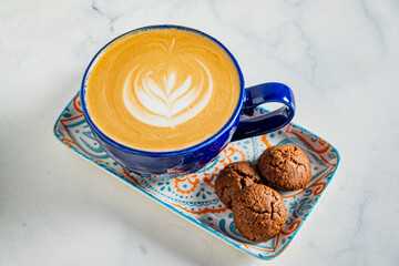 Enjoying a rich cup of coffee beautifully topped with latte art next to freshly baked cookies