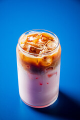 A colorful iced coffee drink in a clear glass, showcasing layers of milk and coffee over ice
