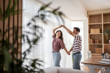 Happy couple dancing and enjoying time together in modern living room