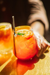 Vibrant drinks with citrus and mint rest on a warm wood surface, inviting enjoyment