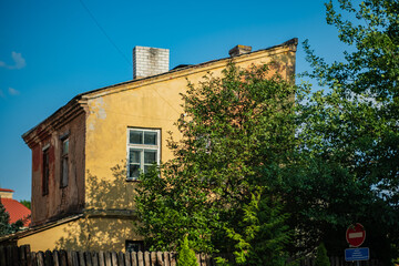 A vintage yellow house with lush trees nearby creates a serene atmosphere in the neighborhood
