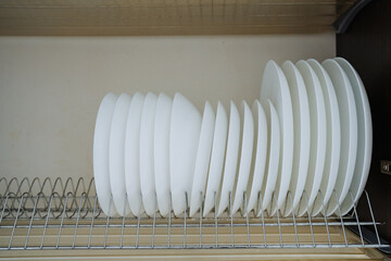 A collection of white plates is neatly stacked and organized on a wire rack, making it easy to...