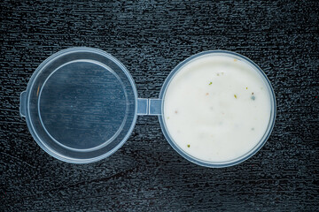 Lush, creamy sauce sits in a clear container, surrounded by rich textured wood, inviting curiosity