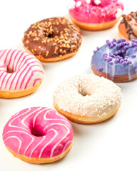 Colorful assortment of donuts arranged on a white background showcasing various toppings and flavors