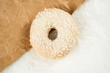 Delicious coconut coated donut resting on crinkled brown paper