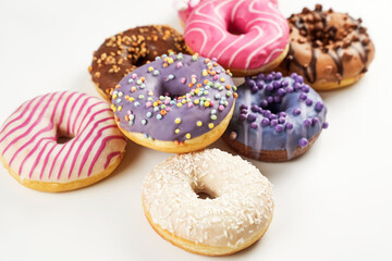 Colorful assortment of donuts with various toppings on a white background, perfect for dessert lovers