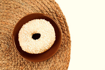 Sweet baked treat with coconut flakes on a woven mat during bright daylight
