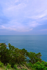 Sunset at Promthep Cape overlooking Nai Harn Beach and just off shore a small island Ko Man in the island of Phuket Thailand. Lush green trees and turquoise waters of the Andaman Sea