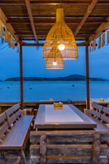 Blue skies at Blue hour Sunset over Rawai Beach in Phuket island Thailand. Restaurants with colourful lanterns lighting up the footpath. Lovely turquoise blue waters, lush green trees and mountains 