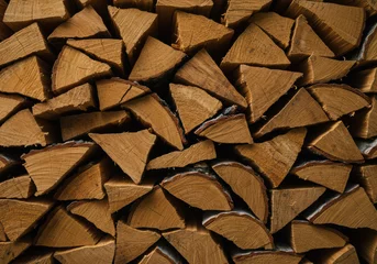 Gordijnen Stack of oak firewood pieces for warmth. Natural wood texture background for rustic interior design or renewable energy and sustainable fuel source theme for banner or post. © CoralFox