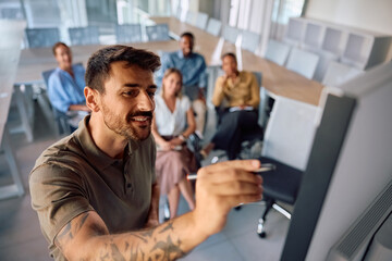 Happy businessman writing on whiteboard during presentation in board room.