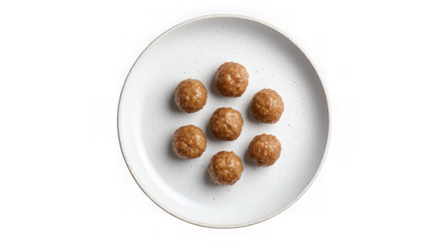 Seven cooked meatballs arranged in a circle on a speckled white plate isolated on transparent background