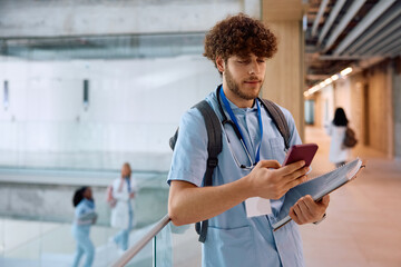 Medical student using smart phone in hallway at university.