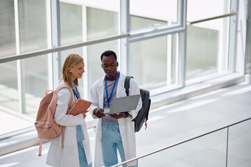 Black student doctor and his female colleague using laptop at medical university.