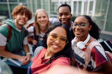 Fototapeta premium Happy Indian student taking selfie with her colleagues at university and looking at camera.