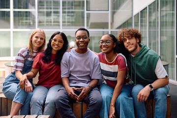 Group of happy diverse students in front of university looking at camera.