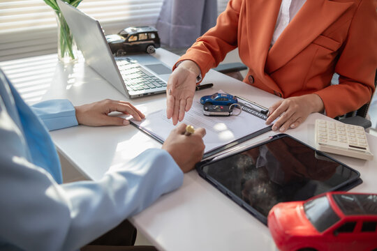 Asian businesswoman agreeing to sign a contract to buy a car from a car dealer for business use. Image of a businesswoman and a car dealer agreeing to sign a contract to buy a car from dealer.