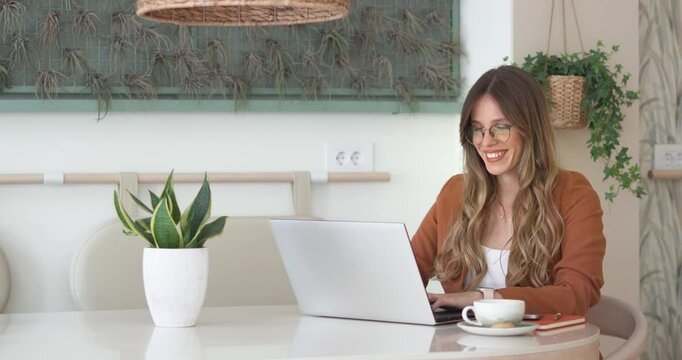 30s mid age European business woman CEO using laptop for work sitting at table in modern cafe. Smiling Latin Hispanic female professional businesswoman using pc digital computer