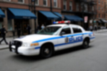 Blurry photo of a police car patrolling the busy city center.