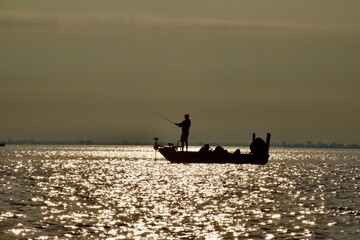 Angler fishing at sunrise in a boat