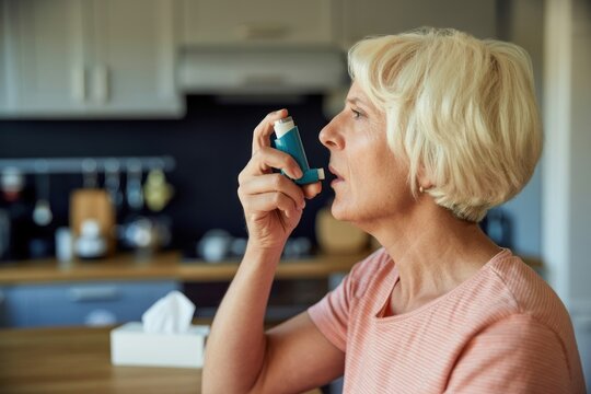 Woman using an inhaler with a kitchen background and tissue box on the table nearby indoors