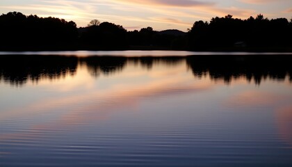 Fototapeta premium the image shows a tranquil landscape during what appears to be dawn or dusk, in the foreground, there is a calm body of water, possibly a lake or pond