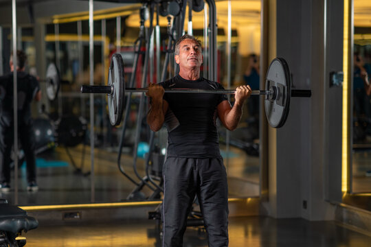 Middle aged man lifting weights in gym