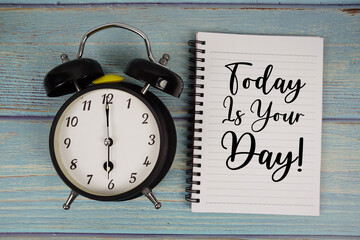 Today Is Your Day! text written on notepad with alarm clock on wooden background