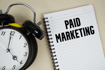Paid Marketing text written on notepad with alarm clock