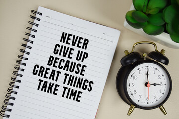 Never give up because great things take time text written on notepad with alarm clock