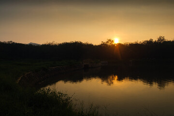 Serene Sunset Landscape Over a Peaceful Forest and Still River Reflection
