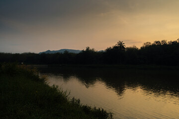 Tranquil Sunset Over a Serene Riverside With Reflections and Silhouetted Trees