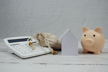 House Model with Caculator and Piggy bank on wooden background