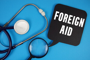 Foreign Aid  text with Stethoscope and magnifying glass on blue background