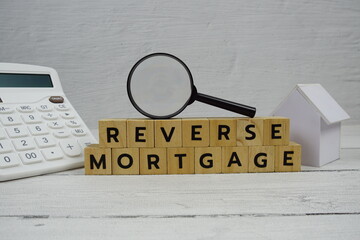 Reverse Mortgage alphabet letters with house model, calculator and magnifying glass on wooden...
