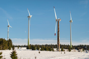 Renewable energy scene in the Czech mountains – three wind turbines, including a rusted historic...