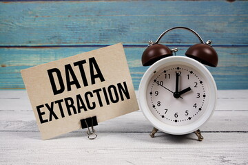 Data Extraction text written on paper card with alarm clock on wooden background