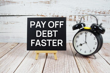 Pay Off Debt Faster text with easel and alarm clock on wooden background