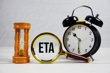 ETA abbreviation of Estimated Time Of Arrival text with alarm clock on wooden background
