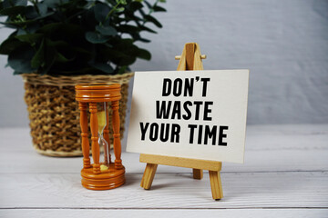 Don't Waste Your Time text with hourglass on wooden background