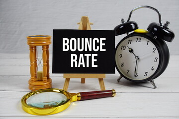 Bounce Rate text with magnifing glass, hourglass and alarm clock on wooden background